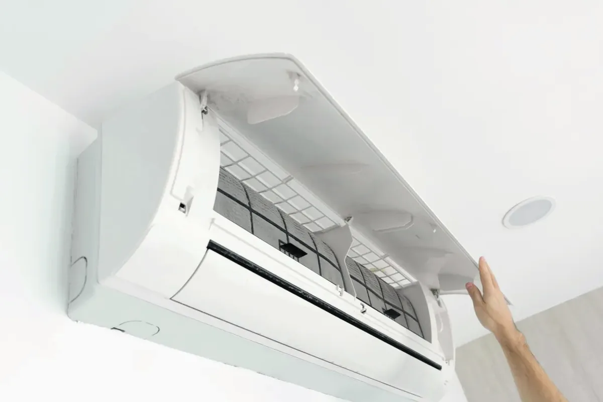 Hand opening the cover of a wall-mounted ductless air conditioner